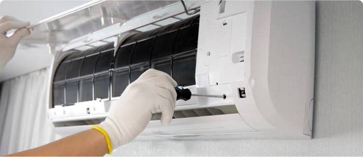 Gloved technician servicing an indoor wall-mounted air-conditioning unit
