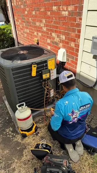 Technician checking outdoor air-conditioning equipment beside a brick home